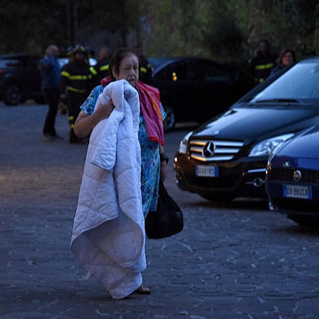 epa05508129 A woman walks next to cars after she had to spend the night on a street after an earthquake in Norcia, Italy, 24 August 2016. A 6.2 magnitude earthquake hit 10km South East of Norcia, central Italy, early 24 August. EPA/MATTEO CROCCHIONI